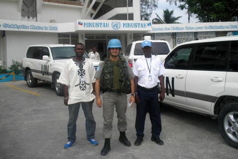 Capitão Tales Américo Osório  de capacete azul em frente a um posto da ONU, tendo ao lado dois homens posado para a foto